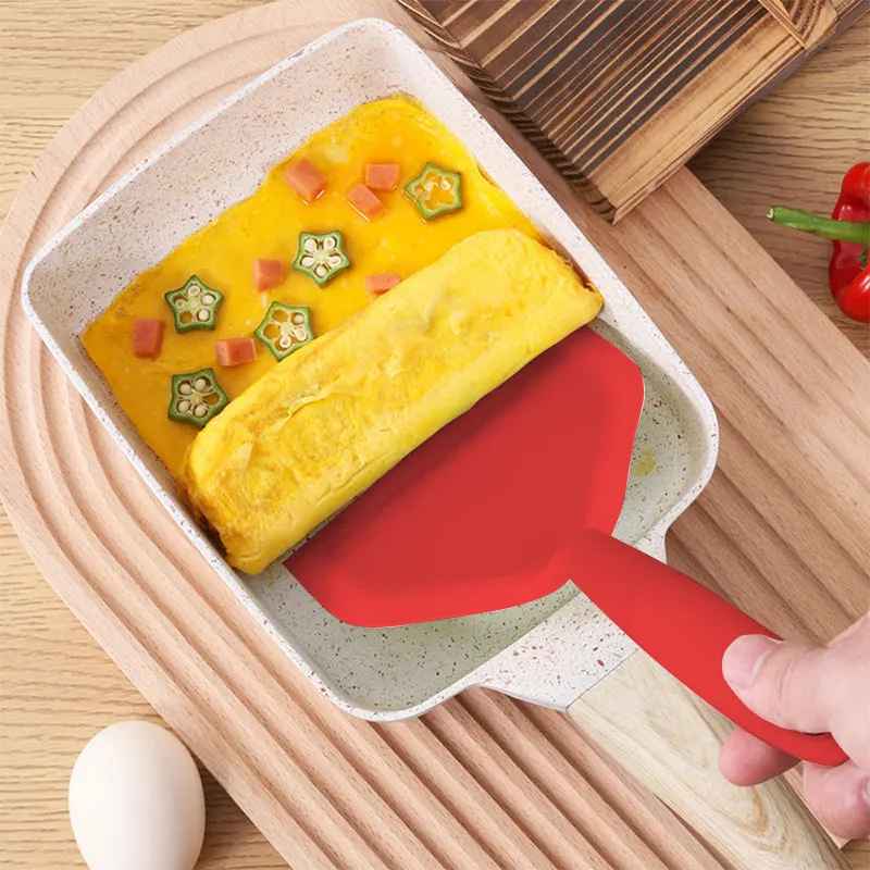 poele tamagoyaki roulee omelette avec spatule rouge